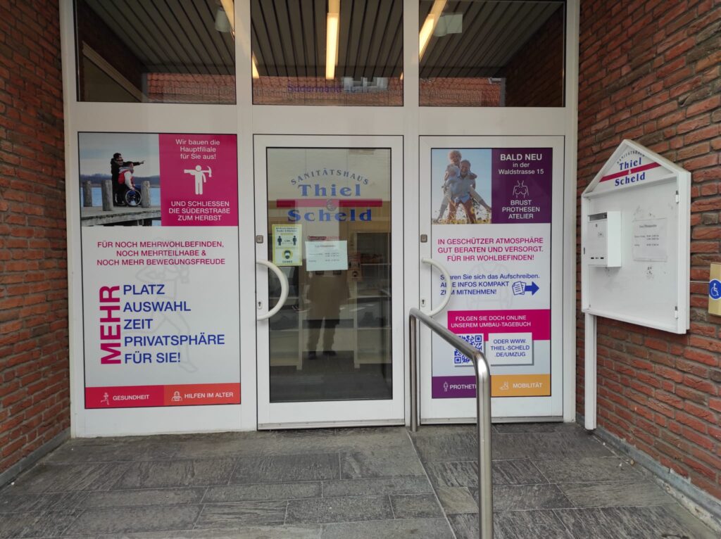 Firmenschilder in Rendsburg 1 Eingangsbereich des Sanitätshauses Thiel und Scheld in Flensburg mit großflächigen Werbefolien an den Glastüren, die auf den Umbau der Hauptfiliale und ein neues Brustprothesenatelier in der Waldstraße 15 hinweisen.