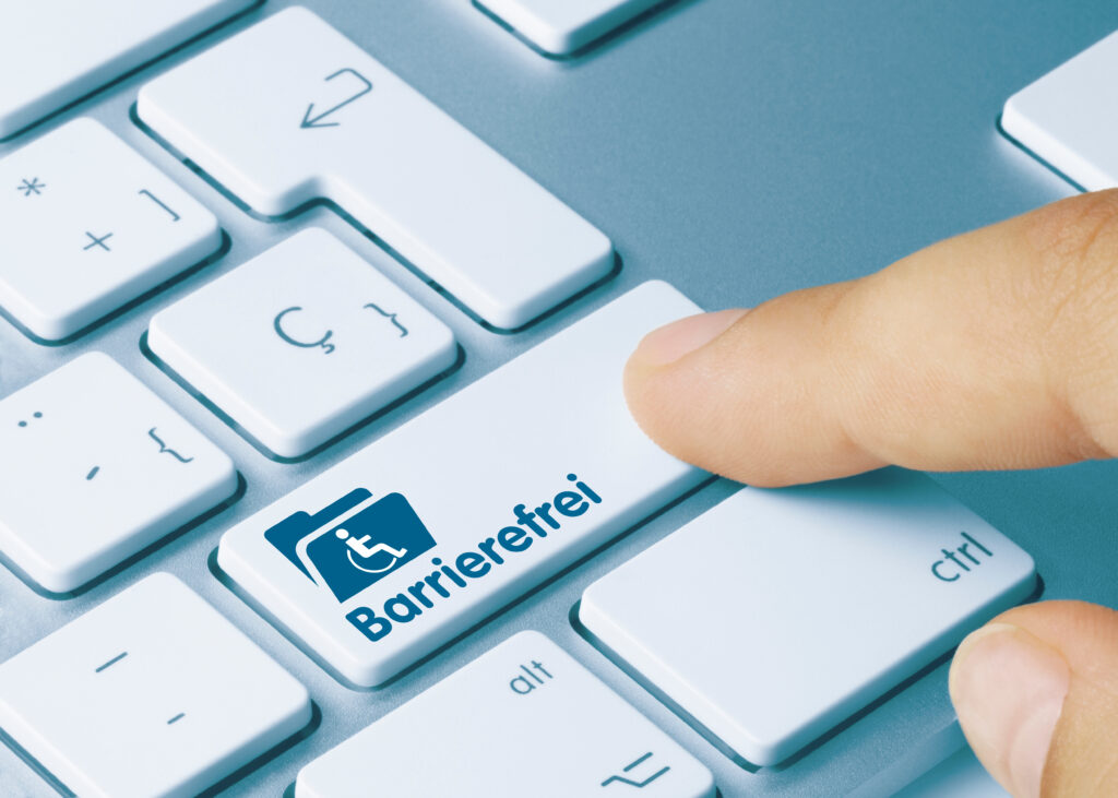 Ein Zeigefinger drückt auf eine Computertastaturtaste mit dem Rollstuhlsymbol und der Aufschrift Barrierefrei.